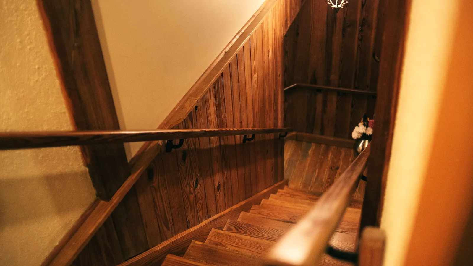 Houten trap met leuning in een warm verlichte hal