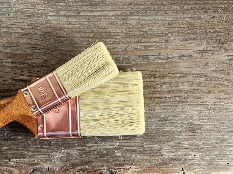 Twee verfkwasten op een houten ondergrond